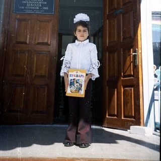 Young girl in first-day school uniform holding a book.
