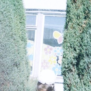 Young girl holding book outside school building.