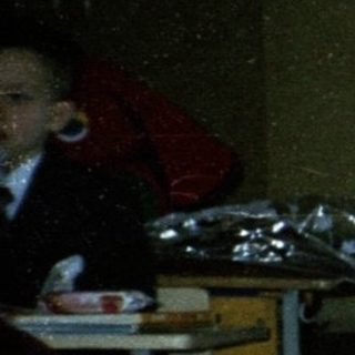 Children in school uniforms eating in cafeteria.