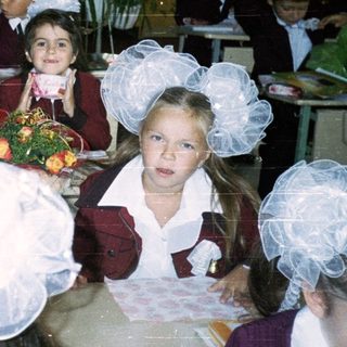 Children in school uniforms eating in cafeteria.