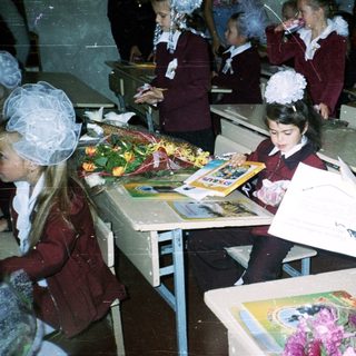 Schoolchildren in formal attire crafting graduation bouquets.