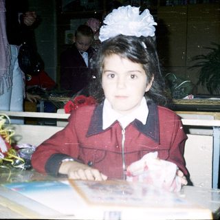 Young girl in school uniform at classroom desk.