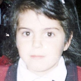 Young girl in school uniform at classroom desk.