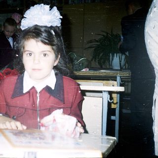 Young girl in school uniform at classroom desk.