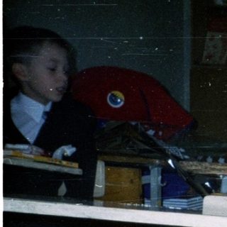 Girl in school uniform holding graduation gift basket.