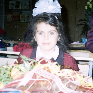 Girl in school uniform holding graduation gift basket.