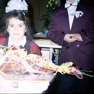 Girl in school uniform holding graduation gift basket.