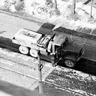 Vintage truck on snowy railway crossing.