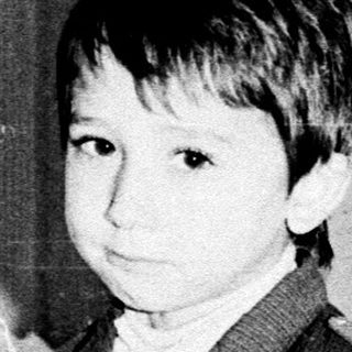 Young boy in vintage suit, seated indoors.