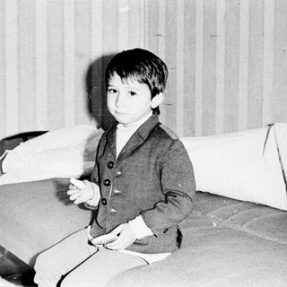 Young boy in vintage suit, seated indoors.