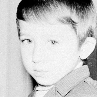 Young boy in vintage suit, early 1900s-style portrait.