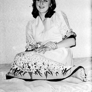 Woman sitting on floor wearing floral dress and lace top.