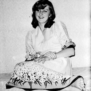 Woman sitting on floor wearing floral dress and lace top.