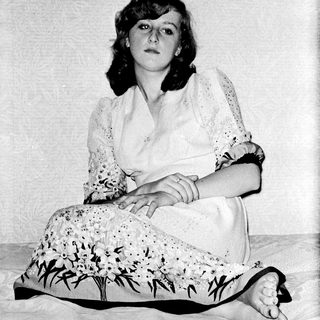 Young woman in vintage dress sitting with cat.