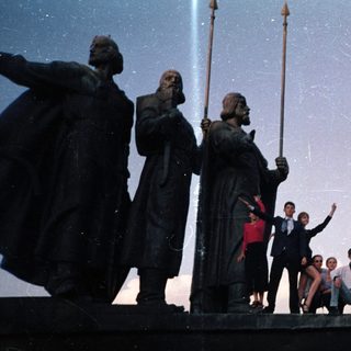 Group posing on historic ship statue.