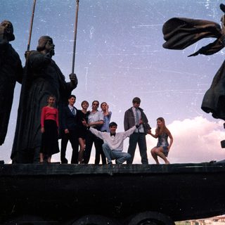 Group posing on historic ship statue.