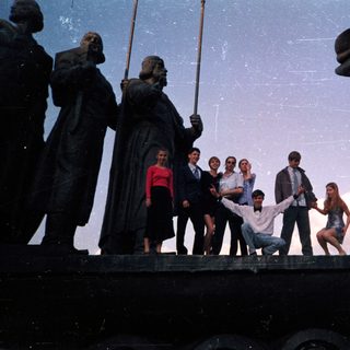 Group posing on historic ship statue.