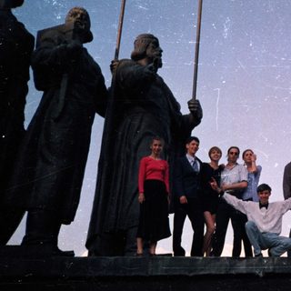 Group posing on historic ship statue.
