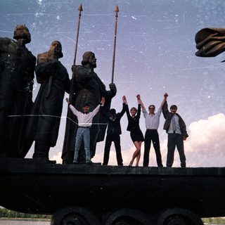 People posing on monument with historical figures.