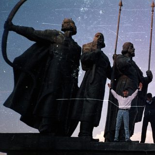 People posing on monument with historical figures.