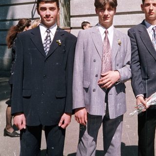 Three young men in formal attire posing outdoors.