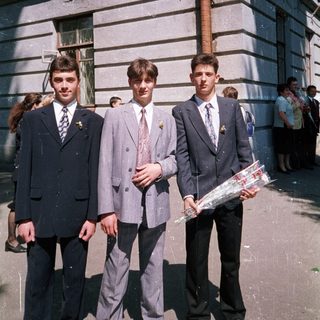 Three young men in formal attire posing outdoors.
