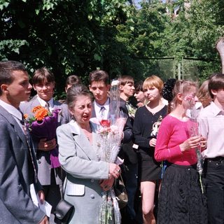 Graduating students presenting flowers to a woman.