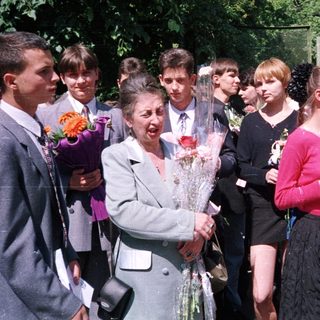 Graduating students presenting flowers to a woman.