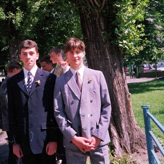 Two young men in formal school attire posing outdoors.