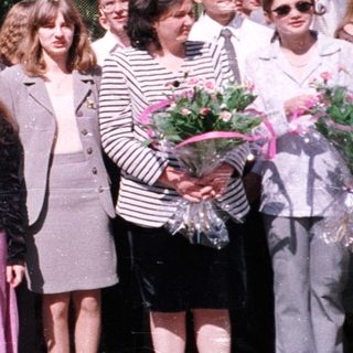 Group of students in formal attire holding flowers.