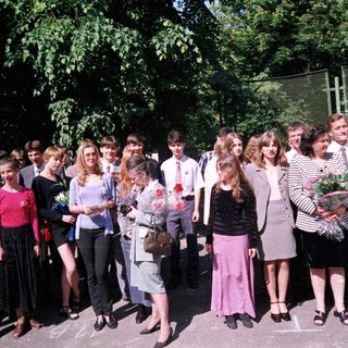 Group of students in formal attire holding flowers.