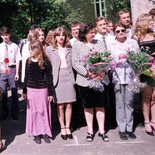 Group of students in formal attire holding flowers.