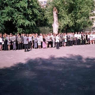 Group of people holding tall flagpole with statue.