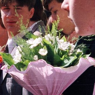 Group of students holding flowers outdoors.
