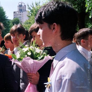 Group of students holding flowers outdoors.