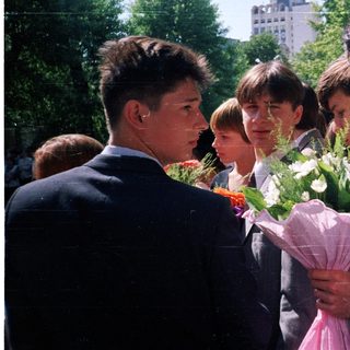 Group of students holding flowers outdoors.