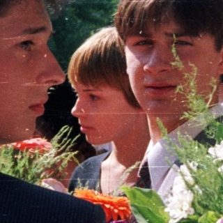 Group of students holding flowers outdoors.
