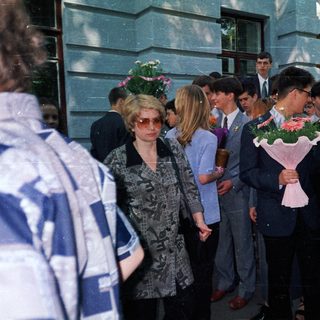 Graduation ceremony with students holding flower bouquets.