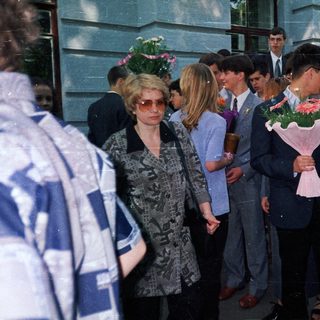 Graduation ceremony with students holding flower bouquets.