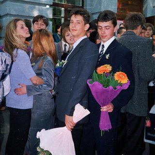 Prom or graduation ceremony with students holding flowers.