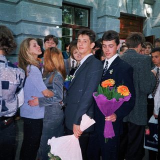 Prom or graduation ceremony with students holding flowers.