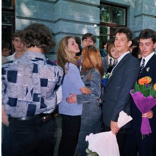 Prom or graduation ceremony with students holding flowers.