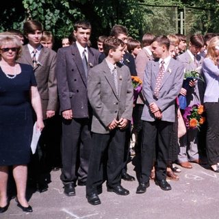 Graduating students holding flowers with teachers.