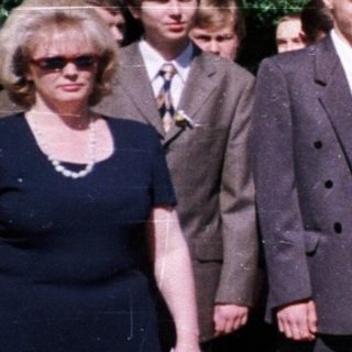 Graduating students holding flowers with teachers.