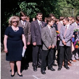 Graduating students holding flowers with teachers.