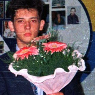 Graduating students holding flowers in school hall.