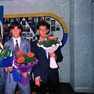 Graduating students holding flowers in school hall.