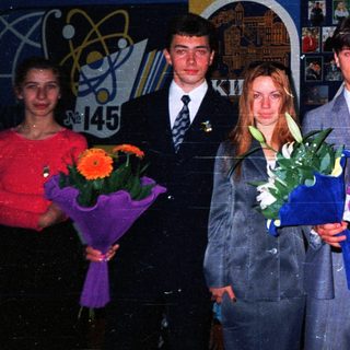 Graduating students holding flowers in school hall.