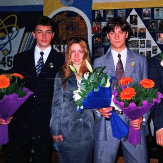 Graduating students holding flowers in school hall.