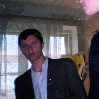 Two people in dimly lit room with vintage decor.